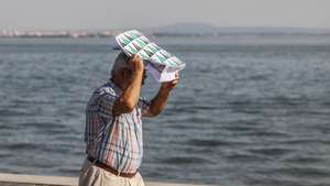Um homem protege-se do calor com um saco de papel junto ao rio tejo esta tarde em Lisboa, 03 de setembro de 2026. distritos estão sob aviso amarelo hoje e amanhã devido à previsão e tempo quente, com valores elevados da temperatura máxima, segundo o Instituto Português do Mar e Atmosfera (IPMA). MIGUEL A. LOPES/ LUSA