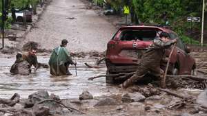 epa13290575 People walk through an area affected by a mudslide in Las Condes, Chile, 08 October 2026. Chile's National Disaster Prevention and Response Service (Senapred) said intense rainfall triggered the mudslide after ravines in the area were activated, sweeping away vehicles and a public transport bus.  EPA/JAVIER TORRES