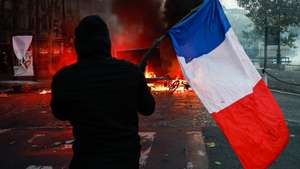 epa13312289 A protester carrying a French flag faces police at Place de la Madeleine during a demonstration against rising living costs and cuts to public services in Paris, France, 17 October 2026. The nationwide mobilization brought together Yellow Vest (Gilets Jaunes) activists, high school and university students, trade unions and other groups protesting rising living costs, fuel prices and deteriorating public services, while demanding improvements in education and school conditions.  EPA/MOHAMMED BADRA
