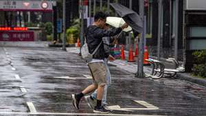epa13324708 A couple braces against wind and rain under an umbrella while crossing a street during Typhoon Champi in Taipei, Taiwan, 23 October 2026. Typhoon Champi brought heavy rainfall that raised concerns over urban flooding and low road visibility in northern cities.  EPA/CHENG-CHIA HUANG