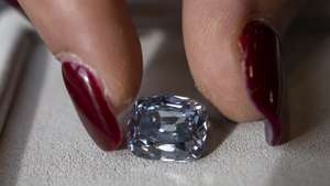 epa10283578 A Sotheby's employee displays a De Beers fancy vivid blue 5.53 carat diamond, during a preview at Sotheby's in Geneva, Switzerland, 03 November 2022. It is estimated to sell at 11,000,000 - 35,000,000 Swiss Francs. The auction will take place in Geneva on November 09.  EPA/MARTIAL TREZZINI