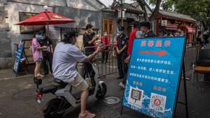 epa09394562 A man wearing a protective face mask shows his health code to the security guards to enter the Nanluoguxiang alley amid the coronavirus pandemic in Beijing, China, 04 August 2021. China's National Health Commission reported 71 locally transmitted Covid-19 cases for 03 August. The coronavirus outbreak, caused mainly by the Delta variant, was first detected on 20 July in Nanjing, Jiangsu province, and has already infected more than 400 people and spread in 25 cities including Wuhan city, where the coronavirus first emerged, and the capital Beijing.  EPA/ROMAN PILIPEY