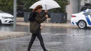 Uma traseunte passa com chapéu de chuva na zona de Algés em Oeiras num dia de temporal, 14 de dezembro de 2022. TIAGO PETINGA/LUSA