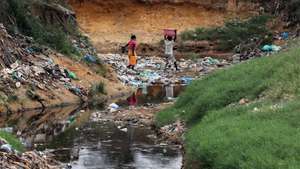 Habitantes atravessam uma enorme vala onde se acumulam detritos e águas paradas no Bairro Paraíso, conhecido pelos níveis elevados de pobreza e criminalidade, a doença e a morte vieram afligir ainda mais os moradores, em Luanda, 09 de janeiro de 2025. Pelo menos cinco pessoas foram oficialmente proclamadas vítimas de cólera, doença ligada à contaminação fecal associada à falta de saneamento e tratamento de água e má higiene, e os habitantes estão preocupados pedindo a intervenção das autoridades angolanas. (ACOMPANHA TEXTO DA LUSA DO DIA 12 DE JANEIRO DE 2025). AMPE ROGÉRIO/LUSA