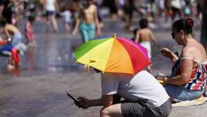 epa12995286 A person uses an umbrella to shelter from the sunshine at Granary Square during a heatwave in London, Britain, 26 May 2026. The record for the hottest May day on record in the UK is broken again with 35 Celsius degrees recorded in London during the heatwave. The UK Health Security Agency has issued an amber heat health alert for south-west England, bringing the number of amber alerts during the heatwave to six.  EPA/TOLGA AKMEN