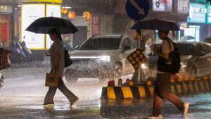 epa13063449 People walk across the street during a downpour of rain in Taipei, Taiwan, 25 June 2026. The local authorities in Hualien County ordered evacuations in parts of Wanrong and Fenglin following a yellow alert that a nearly full upstream barrier lake might overflow within 48 hours. Rainfall tied to Severe Tropical Storm Mekkhala was expected, prompting officials to open shelters and step up monitoring of key roads and facilities.  EPA/RITCHIE B. TONGO