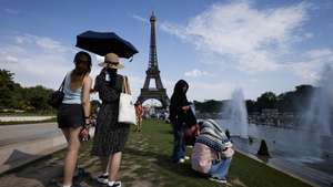 epa13052299 Women shelter from the heat under an umbrella at the Trocadero Fountain by the Eiffel Tower, in Paris, France, 20 June 2026. An intense heatwave is gripping Western and Central Europe, pushing temperatures far above seasonal norms for mid-June.  EPA/YOAN VALAT