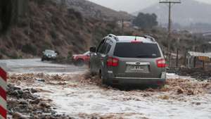 epa13123890 A vehicle drives through a flooded road after Los Loros Creek overflowed in La Serena, Chile, 20 July 2026. President Jose Antonio Kast declared a state of constitutional exception of catastrophe for the Coquimbo Region and Huasco province in the Atacama Region in response to damage caused by the frontal system.  EPA/HERNAN CONTRERAS
