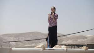epa04205229 An Israeli settler prays on the roof of her house as she refused to step down, during a demolition operation in the West Bank illegal settlement of Maale Rehavam, on 14 May 2014. The Israeli Supreme Court rule that until 18 May the illegal structures in the settlements of Ma'aleh Rehavam, Ramat Gilad, and Givat Asaf need to evacuate because they are erected on Palestinians private land.  EPA/ABIR SULTAN
