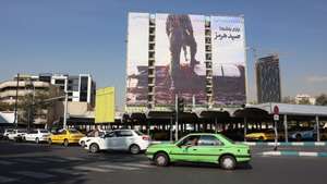 epa13302661 Iranians drive past an anti-US billboard depicting a member of Iran's Revolutionary Guard (IRGC) placing his foot on a US unmanned underwater vehicle that Iran claims to have seized in the Strait of Hormuz, with the Persian words 'Hormuz Catch', in Vanak Square in Tehran, Iran, 14 October 2026, amid the ongoing conflict between Iran and the United States.  EPA/ABEDIN TAHERKENAREH RESTRICTIONS: NO Access Israel Media/Persian Language TV Stations Outside Iran/Strictly No Access BBC Persian/VOA Persian/Manoto TV/Iran International TV. (As mandated by Iran's Directorate General for Foreign Media) --