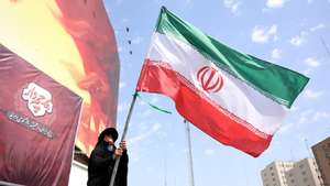 epa13175371 An Iranian woman flies Iran's national flag at the Valiasr square in Tehran, Iran, 17 August 2026.  Iranian Army chief Amir Hatami announced a 30,000 US dollar bounty for killing or capturing US military personnel, offering double the reward for Iranian women who carry out the action, according to Iranian state media.  EPA/ABEDIN TAHERKENAREH RESTRICTIONS: NO Access Israel Media/Persian Language TV Stations Outside Iran/Strictly No Access BBC Persian/VOA Persian/Manoto TV/Iran International TV. (As mandated by Iran's Directorate General for Foreign Media) --