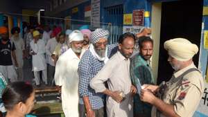 epa11383132 Indian voters have their ID papers checked by an armed security officer as they queue during the seventh and last phase of the Indian parliament elections outside a polling station on the outskirts of Amritsar, Punjab, India, 01 June 2024. General elections in India are held over seven phases between 19 April and 01 June 2024, which are held every five years and about 968 million people are eligible to vote. Results will be announced on 04 June 2024 for India's 545-member lower house of parliament, or Lok Sabha.  EPA/MANU ARORA