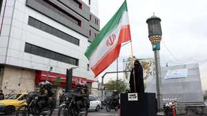 epa12884570 Iranian security forces drive past a woman holding an Iranian flag on a street in Tehran, Iran, 12 April 2026. Iran and the United States have failed to reach an agreement after peace talks were held in Islamabad on 11 April.  EPA/ABEDIN TAHERKENAREH