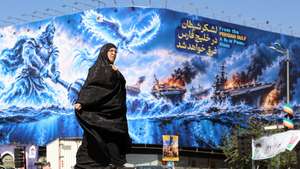 epa13253679 A veiled Iranian woman walks next to an anti-US billboard carrying a sentence in Persian that reads, 'The devil army will be drowned in the Persian Gulf,' at Enghelab Square in Tehran, Iran, 21 September 2026. The conflict between the US and Iran continues, with both sides exchanging threats.  EPA/ABEDIN TAHERKENAREH RESTRICTIONS: NO Access Israel Media/Persian Language TV Stations Outside Iran/Strictly No Access BBC Persian/VOA Persian/Manoto TV/Iran International TV. (As mandated by Iran's Directorate General for Foreign Media) --