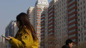epa12824515 People walk past condominium buildings in Beijing, China, 16 March 2026. According to the National Bureau of Statistics, new home prices in 70 cities fell 3.2 percent year‑on‑year in February 2026, marking the 32nd consecutive month of contraction and the biggest drop since June.  EPA/JESSICA LEE