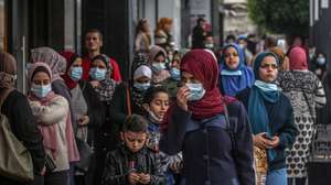epa08867655 Palestinians wearing protective face masks walk in the market amid the ongoing coronavirus COVID-19 pandemic in Gaza City, 06 December 2020. The Ministry of Interior in Gaza City announced new measures as the number of new infections with the coronavirus increases, which are the closure of schools, universities, mosques, and government ministries until further notice, and work from six in the morning until six in the evening only, and a comprehensive closure on Friday and Saturday of every week.  EPA/MOHAMMED SABER