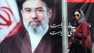 epaselect epa12899721 An Iranian woman walks past a picture of Iran’s Supreme Leader Ayatollah Mojtaba Khamenei on a street in Tehran, Iran, 19 April 2026. Tensions between the United States and Iran continue as the Strait of Hormuz remains blocked.  EPA/ABEDIN TAHERKENAREH