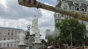 epa13063725 A worker cleans the monument to Princess Olga next to an exhibition of destroyed Russian military machinery on Mykhailivska Square in Kyiv, Ukraine, 25 June 2026, amid the ongoing Russian invasion. Specialists of the Ukrainian multi-service company 'INVITE' are opening and cleaning significant monuments in Kyiv after their protective conservation, which was carried out at the start of the Russian invasion in 2022.  EPA/SERGEY DOLZHENKO