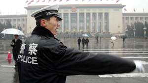 A Chinese policeman directs traffic outside the Great Hall of the People prior to a plenary session of the National People's Congress (NPC) in Beijing 11 March 2003.  China arrested 3,402 people for endangering state security last year, as the fight to wipe out separatism, terrorism and religious extremism was stepped-up.                               AFP PHOTO/GOH Chai Hin