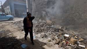 epa13003354 A person shields themselves from smoke rising from a trash fire in Havana, Cuba, 29 May 2026.  EPA/ERNESTO MASTRASCUSA
