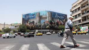 epa12194168 An Iranian man crosses a street near an anti-Israeli billboard reading in Persian 'Now is our turn' in Tehran, Iran, 24 June 2025. Israel's military on 24 June, accused Iran of violating a ceasefire by launching missiles into Israeli airspace. Iran's General Staff of the Armed Forces Abdolrahim Mousavi denied firing any missiles towards Israel, Iranian state media reported.  EPA/ABEDIN TAHERKENAREH