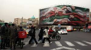 epaselect epa12661003 Iranians walk next to a billboard reading in Persian 'Iran is our homeland' in street in Tehran, Iran, 19 January 2026. Iran is experiencing a nationwide internet blackout that began on 08 January 2026, amid an intensifying wave of anti-government protests.  EPA/ABEDIN TAHERKENAREH