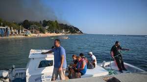 epa13167144 Residents and holidaymakers are transported by boats during a wildfire in Siviri, Halkidiki, Northern Greece, 13 August 2026. An operation is under way to evacuate people from Siviri Beach in Halkidiki as a large wildfire continues to rage in the area.  EPA/STRINGER