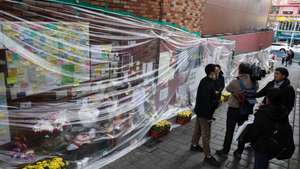 epa10333602 Flowers and messages are covered with plastic amid rain at a makeshift memorial space near the site of the Itaewon tragedy in Seoul, South Korea, 28 November 2022. The Halloween crowd crush left 158 people dead.  EPA/YONHAP SOUTH KOREA OUT