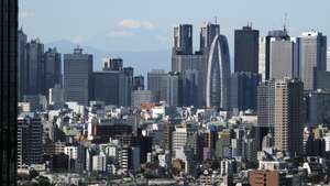 epaselect epa04475436 Japan's highest peak Mt Fuji is seen through Tokyo's Shinjuku skyscrapers in Tokyo, Japan, 04 November 2014. Japan's stocks surge and exporters traded broadly higher as the yen fell further against major currencies after the Bank of Japan's decision on 31 October additional monetary easing. The bank said it will boost the amount of money it pumps into the economy each year by ten to 20 trillion yen (91 billion to 182 billion US dollar).  EPA/KIMIMASA MAYAMA