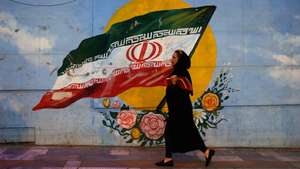 epa07492362 An Iranian woman walks next to a wall painting of Iran's national flag in a street of Tehran, Iran, 08 April 2019. The US government on 08 April 2019 said it had designated Iran's revolutionary guards corps (IRGC) as a terrorist organization, marking the first time a US government has made such a designation on a foreign government's organization.  EPA/ABEDIN TAHERKENAREH