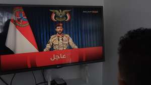 epa13322226 A person watches Houthi military spokesman Yahya Sarea deliver a televised statement in Sanaa, Yemen, 22 October 2026. Sarea said the group had carried out four missile and drone attacks on Saudi positions.  EPA/YAHYA ARHAB