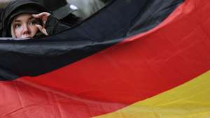 epa11776647 A demonstrator behind a German flag during a right-wing demonstration under the slogan 'For law and order: against left-wing extremism and politically motivated violence', in Berlin, Germany, 14 December 2024.  EPA/HANNIBAL HANSCHKE