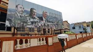 epa13011424 A woman walks past a billboard displaying images of Cuban President Miguel Diaz-Canel (R), General and former President Raul Castro (C), and the late former Cuban President Fidel Castro (L) on 01 June 2026, in Havana, Cuba (issued 02 June 2026). Former Cuban President Raul Castro will turn 95 on 03 June 2026, retired from all formal positions but simultaneously in the spotlight, leading bilateral dialogue with Washington and having been criminally indicted a few days ago in the US.  EPA/Ernesto Mastrascusa