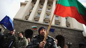 epa02621779 A Bulgarian farmer holds a national flag during a protest in Sofia, Bulgaria, 08 March 2011. The association demands changes in the Income Tax Act, according to which individual farmers have to pay taxes on 40% of their incomes. The farmers will also demand restoration of the excise duty on fuels and provision of land from municipal and state pastures.  EPA/VASSIL DONEV
