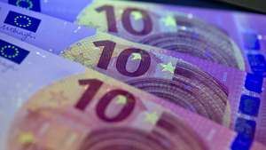 epa04194865 The special security features of the new 10-euro banknote, visible under a black light lamp, as it is presented at the Bundesbank in Frankfurt Main, Germany, 07 May 2014. The new bill will be introduced on 23 September 2014.  EPA/BORIS ROESSLER