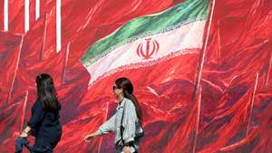 epa13302669 Iranian women walk past a banner featuring Iran’s national flag in a street in Tehran, Iran, 14 October 2026, amid the ongoing conflict between Iran and the United States.  EPA/ABEDIN TAHERKENAREH RESTRICTIONS: NO Access Israel Media/Persian Language TV Stations Outside Iran/Strictly No Access BBC Persian/VOA Persian/Manoto TV/Iran International TV. (As mandated by Iran's Directorate General for Foreign Media) --
