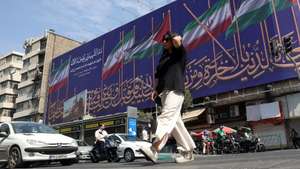 epa13145092 An Iranian woman walks past a billboard displaying the flags of Iran and Palestine on a street in Tehran, Iran, 01 August 2026. Tensions between Iran and the United States over the Strait of Hormuz continue after US President Donald Trump signalled on 31 July 2026 that further US strikes against Iran were possible.  EPA/ABEDIN TAHERKENAREH RESTRICTIONS: NO Access Israel Media/Persian Language TV Stations Outside Iran/Strictly No Access BBC Persian/VOA Persian/Manoto TV/Iran International TV. (As mandated by Iran's Directorate General for Foreign Media) -- RESTRICTIONS: ISRAEL OUT - NO ACCESS ISRAEL MEDIA/PERSIAN LANGUAGE TV STATIONS OUTSIDE IRAN/STRICTLY NO ACCESS BBC PERSIAN/VOA PERSIAN/MANOTO TV/IRAN INTERNATIONAL TV