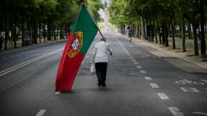 CONJUNTO DE 30 FOTOGRAFIAS SOBRE UM ANO DE ESTADO DE EMERGÊNCIA: 16-30: Foto datada de 25/04/2020: Um homem com uma bandeira de Portugal sobe a Avenida da Liberdade em Lisboa, por volta das 15 horas, altura em que anualmente se realiza um desfile comemorativo do 25 de abril de 1974 e que, devido à pandemia da covid-19, não pode ter lugar, em Lisboa, 25 de abril de 2020. Os 46 anos do 25 de Abril estão a ser hoje celebrados de forma diferente em Portugal, com uma sessão solene reduzida no parlamento, sem o tradicional desfile e com um apelo para que os portugueses cantem a ‘Grândola' à janela. JOSÉ SENA GOULÃO/LUSA