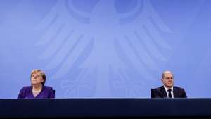 epa09616668 German Chancellor Angela Merkel (L) and Acting German Minister of Finance and Social Democratic Party (SPD) top candidate for the federal elections Olaf Scholz (R) attends a press conference after a video conference with German State Premiers about the current coronavirus situation, at the Chancellery in Berlin, Germany, 02 December 2021  EPA/FILIP SINGER / POOL