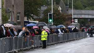 epa10178518 People queue to lay flowers at Holyroodhouse in Edinburgh, Scotland, Britain 11 September 2022. The arrival of the hearse carrying Queen Elizabeth II marks the first stage of the journey towards London. Britain's Queen Elizabeth II died at her Scottish estate on 08 September 2022.  EPA/ADAM VAUGHAN