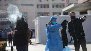 epa10375329 A volunteer health worker gives directions to a patient at Chaoyang hospital in Beijing, China, 21 December 2022.  Chinese authorities have reported five more deaths as fever clinics or consulting rooms and hospital beds have been setup around the country. Covid-19 cases continue to spread as Beijing eases pandemic control measures.  EPA/WU HAO