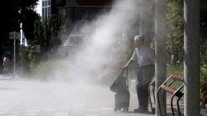 epa12258184 An elderly man sits under a cooling mist station during a heatwave in Tokyo, Japan, 24 July 2025. Temperatures are surging across Japan, with a high of 39.4 degrees Celsius recorded in Kyoto Prefecture, western Japan, according to the Japan Meteorological Agency (JMA).  EPA/FRANCK ROBICHON
