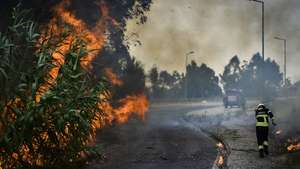 Um bombeiro protege-se do fogo durante o incêndio florestal em Andrinos, às portas da cidade de Leiria, 13 de julho de 2022. Dezasseis dos 18 distritos de Portugal continental estão hoje sob aviso vermelho, o mais grave, devido ao tempo quente, com mais de uma centena de concelhos em perigo máximo de incêndio rural. NUNO ANDRÉ FERREIRA/LUSA
