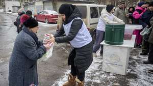 epa12596438 Locals queue to receive a hot meal during a food aid distribution in a residential area of Kharkiv, northeastern Ukraine, 16 December 2025, amid the ongoing Russian invasion. Volunteers cook and distribute food to locals struggling to prepare meals for themselves due to the frequent and long electricity cuts.  EPA/SERGEY KOZLOV
