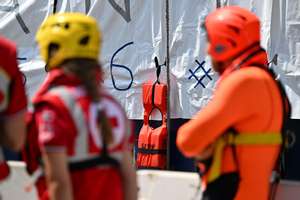 epa11403501 Italian Red Cross members stand next to part of a banner made by the crew of Doctors Without Borders (MSF) search and rescue vessel &#039;Geo Barents&#039; by 11 white bags used to recover the bodies of dead migrants and life jackets with the words reading &#039;Europe...How many more?&#039;, to symbolize the bodies recovered at sea, upon arrival at the port of Genoa, Italy, 11 June 2024. Geo Barents ship docked at the port carrying 165 migrants, mainly from Eritrea, rescued in the Libyan area. Among the rescued migrants are 109 recovered onboard a rubber dinghy and 37 from a fiberglass boat. There are 33 minors on board, around thirty of whom are unaccompanied. While traveling towards Genoa, the ship recovered 11 bodies at sea for migrants who drowned in a previous shipwreck, before they were transferred to a Coast Guard patrol boat near Lampedusa.  EPA/LUCA ZENNARO