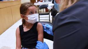 A nurse gives a little girl a shot of the Pfizer COVID-19
