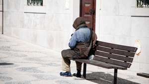 Homeless man on bench in Lisbon, Portugal.