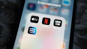 Netflix application icon among Apple TV+, Amazon Prime Video, and HBO GO in Entertainment Folder on Apple iPhone 12 Pro MAX screen close-up. Popular streaming services.
