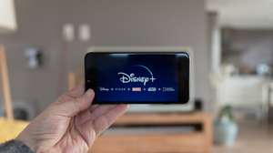 Disney+ startscreen on  mobile phone. Disney+ online video, content streaming subscription service. Man holds his smartphone up and looks at disney plus