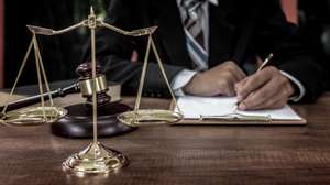 Tribunal attorney lawyer working with documents and wooden judge gavel on table in courtroom.